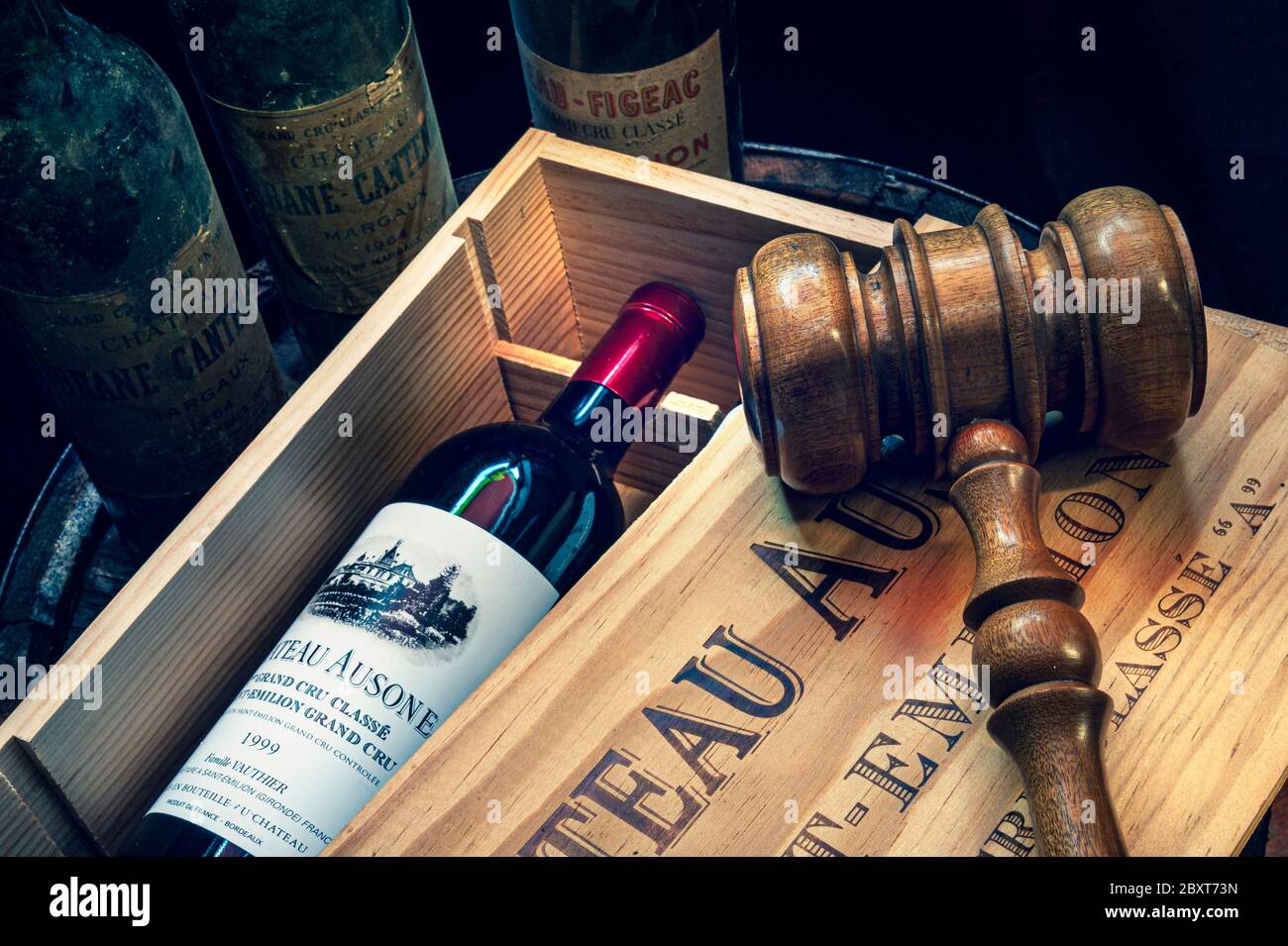 Asta di vino con gavel martello all'asta su cassa aperta di 1999 Chateau Ausone Saint-Émilion vino e altre vecchie bottiglie di vino Bordeaux fine dietro su vecchia cantina cantina botte Francia Foto Stock