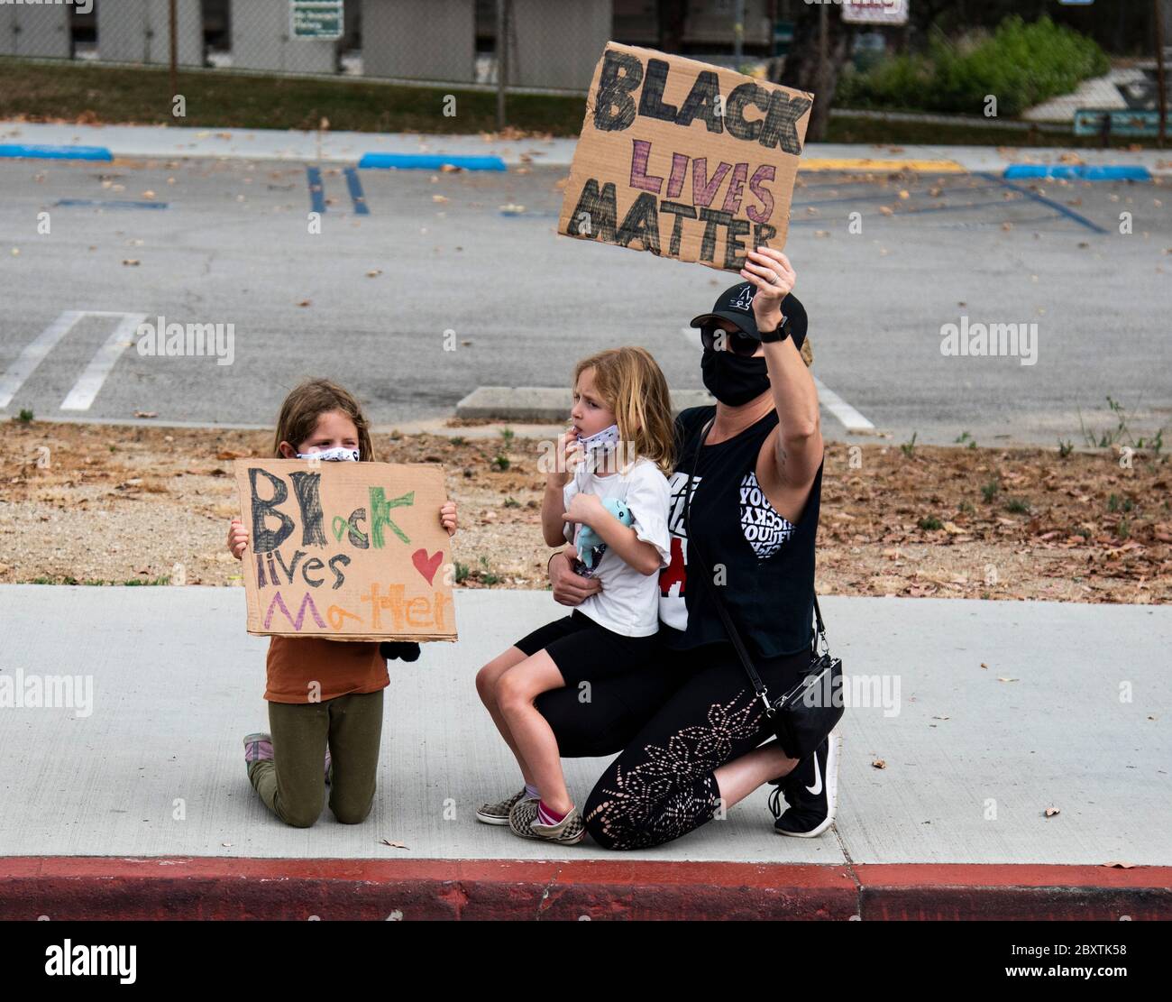 Una madre con i suoi figli protestano con i segni di una manifestazione in onore di George Floyd, nel quartiere di Highland Park a Los Angeles, California Foto Stock