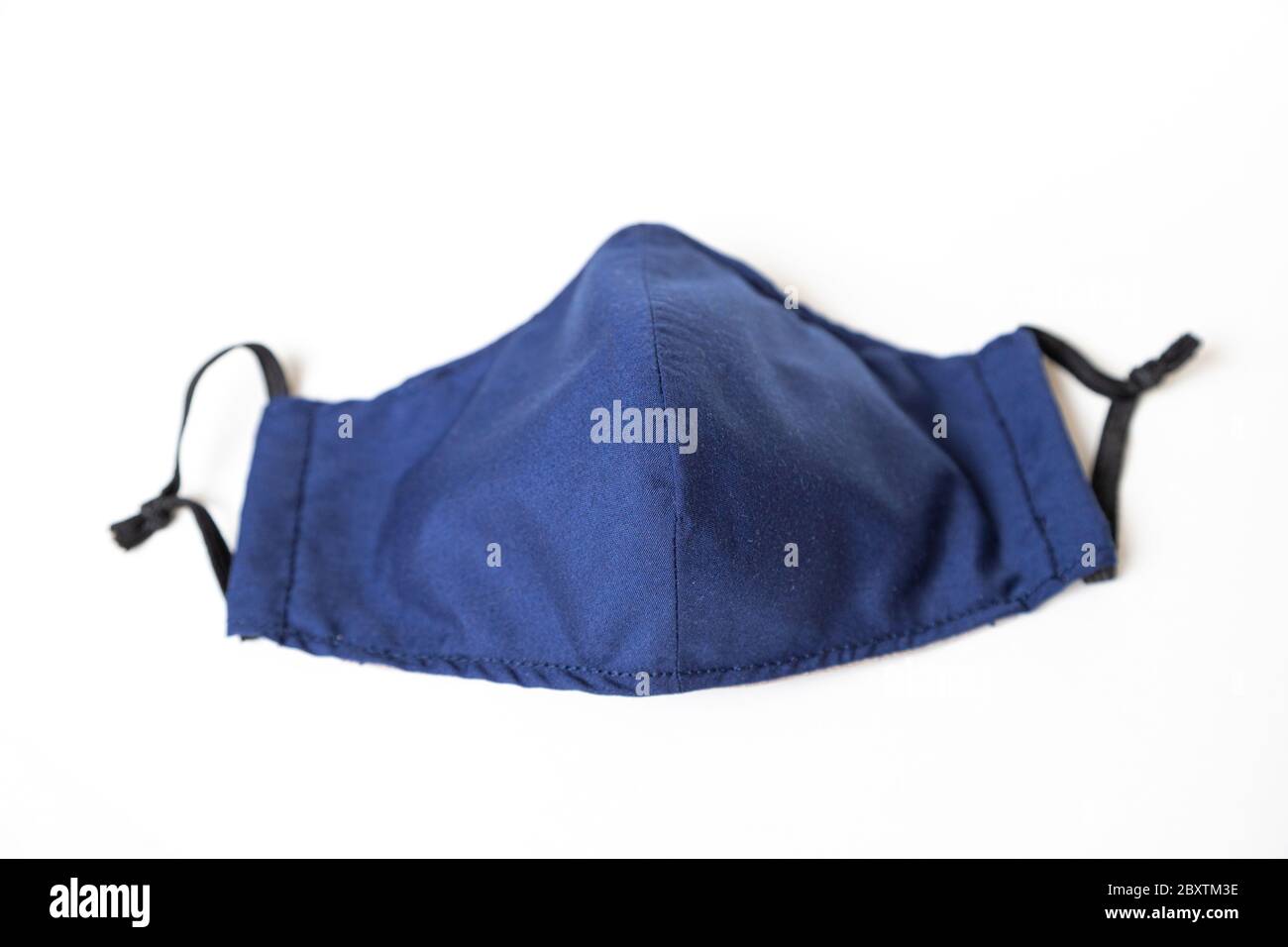 Maschera in tessuto fatta in casa di colore blu isolato su sfondo bianco. Realizzato per il coronavirus Covid-19 per prevenire la diffusione di pandemia. Foto Stock Maschera in tessuto fatta in casa di colore blu isolato su sfondo bianco. Realizzato per il coronavirus Covid-19 per prevenire la diffusione di pandemia. Foto Stock