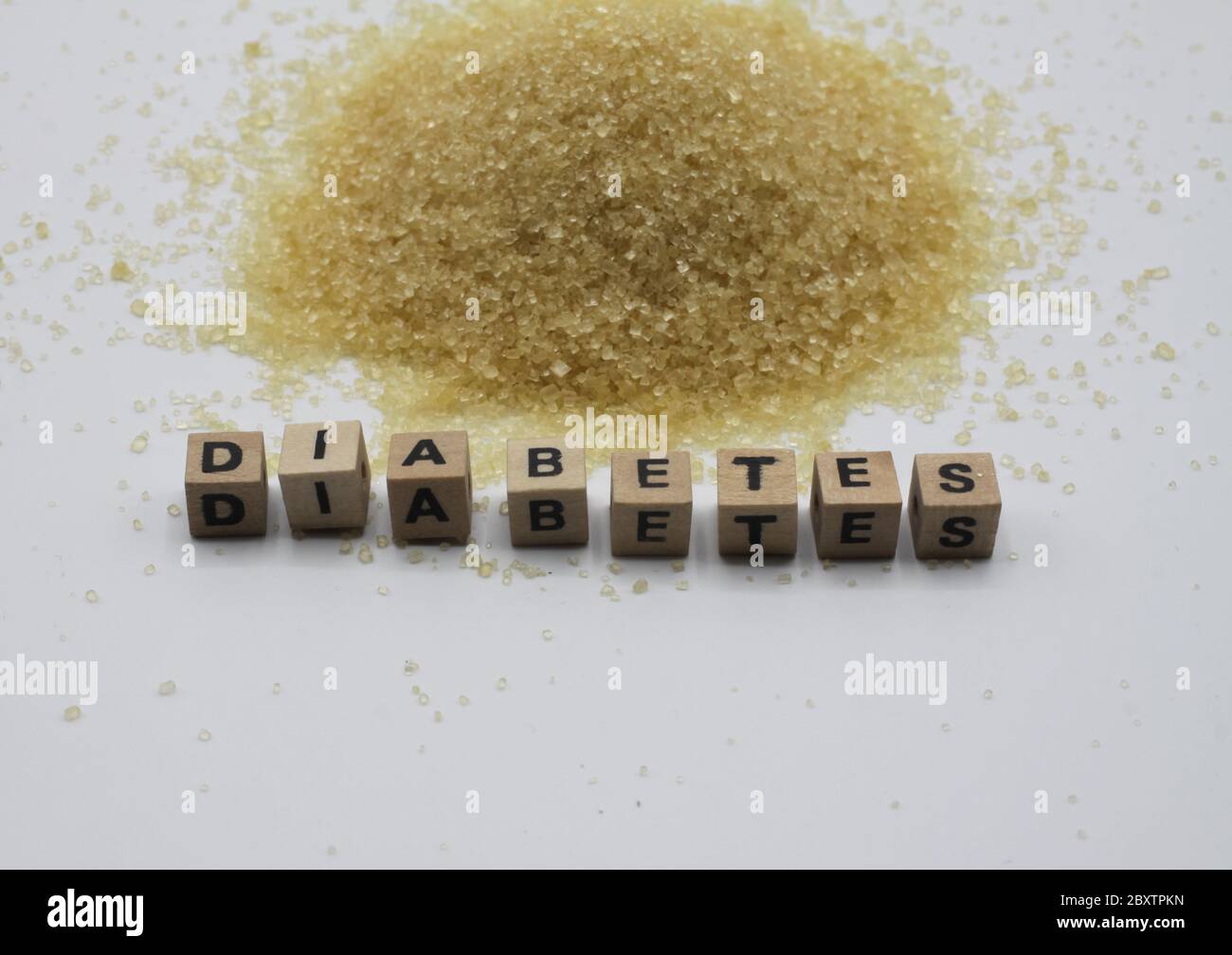 Primo piano di isolati pali di zucchero di canna, sfondo bianco. Parola diabete scritto con piastrelle di legno lettera. Foto Stock