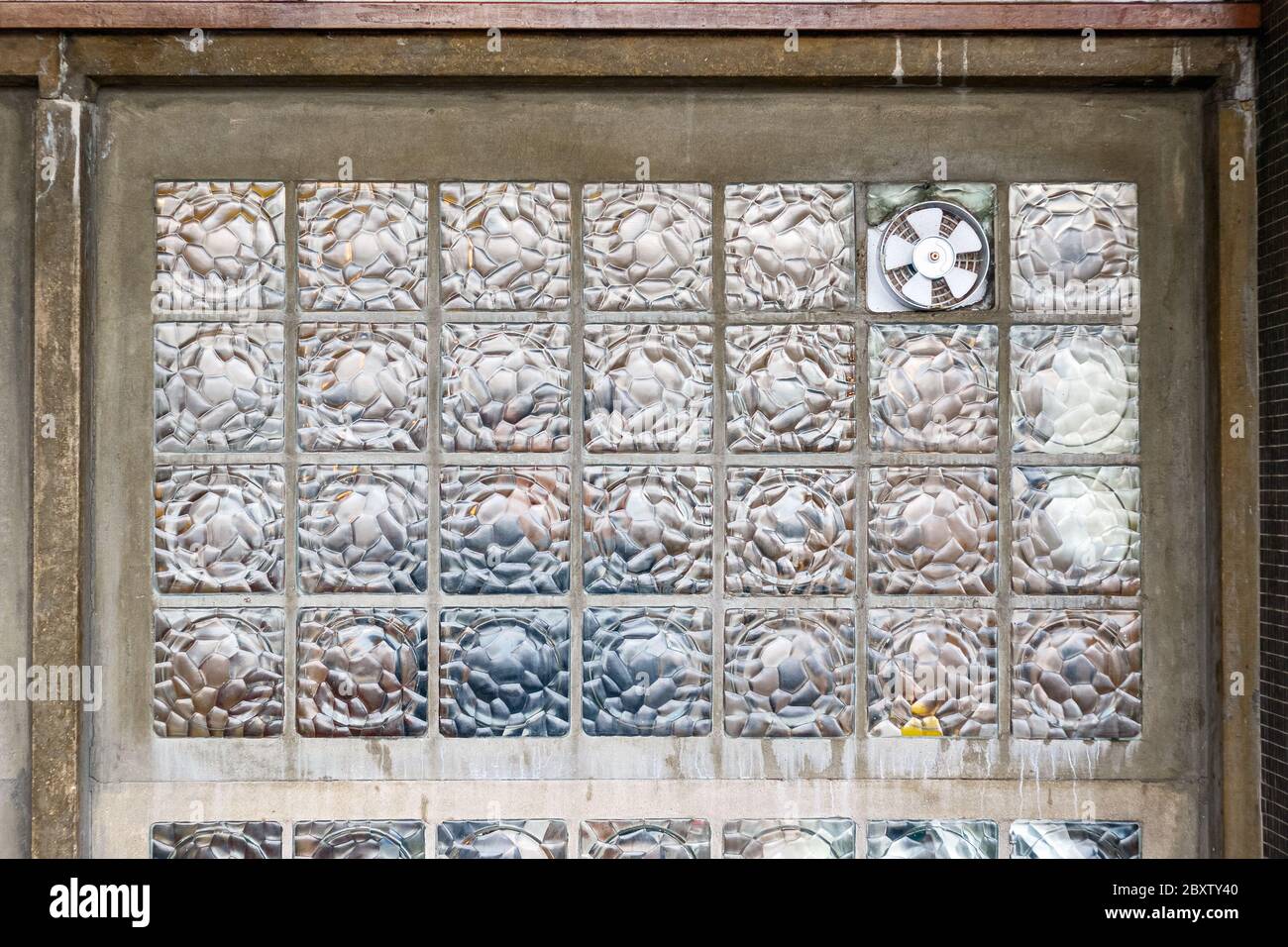 Ventola di aspirazione per ventilazione installata su una parete di blocco in vetro per l'uso in background Foto Stock