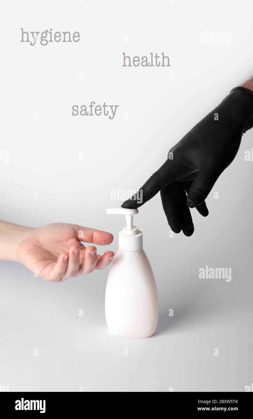 Qualcuno iSomeone in un guanto nero in nitrile dà un gel disinfettante alle mani di un'altra persona senza guanti.There è un posto per text.n un nero n Foto Stock