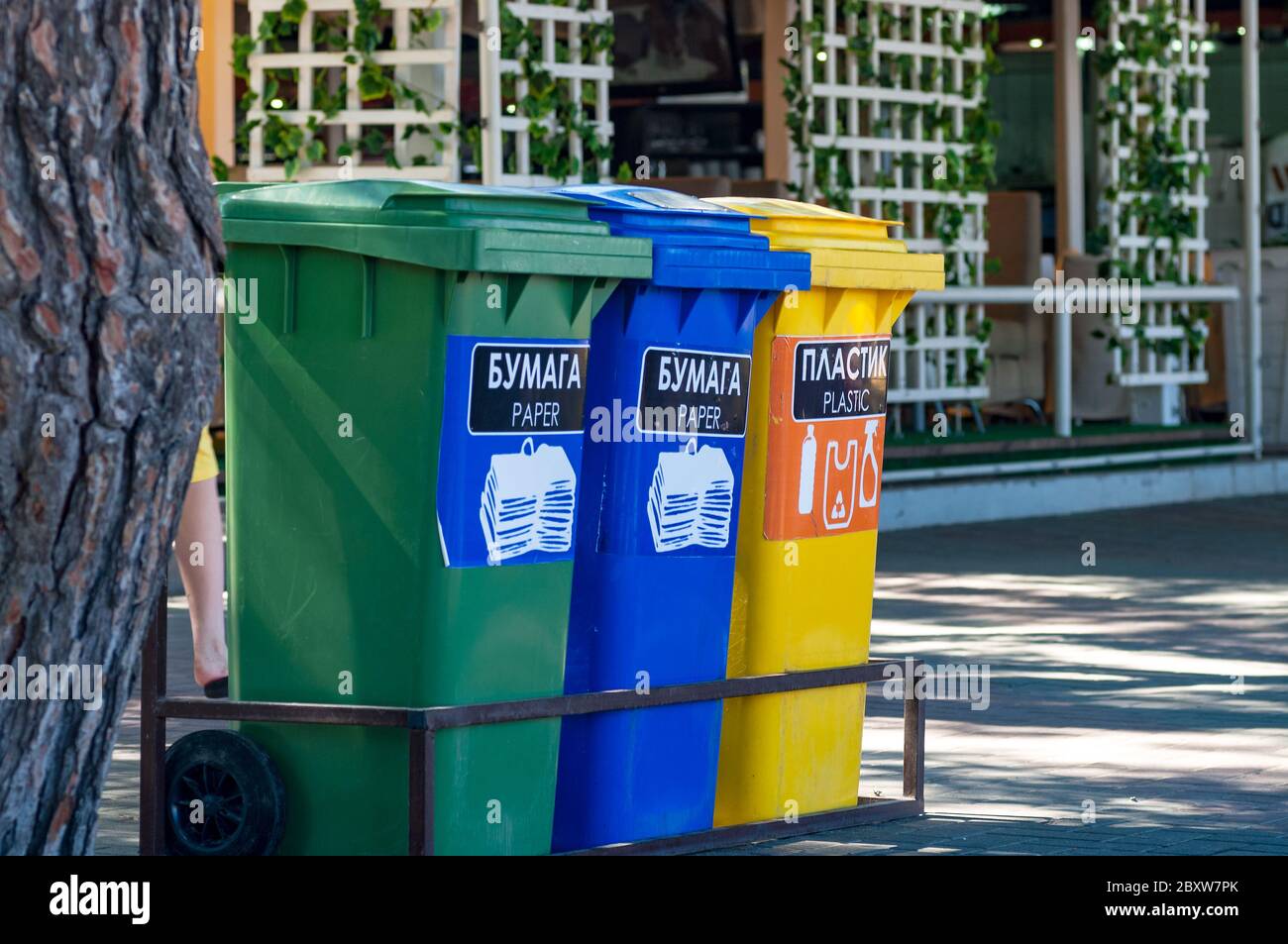 Tre contenitori per il riciclaggio di vetro, plastica e carta su una strada cittadina Foto Stock
