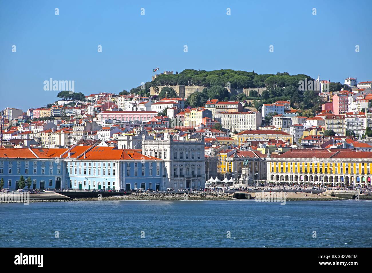 Edifici multicolore della città vecchia di Lisbona. Castello di São Jorge che guarda in basso sulla piazza della città di Praça do Comércio in primo piano. Portogallo. Foto Stock