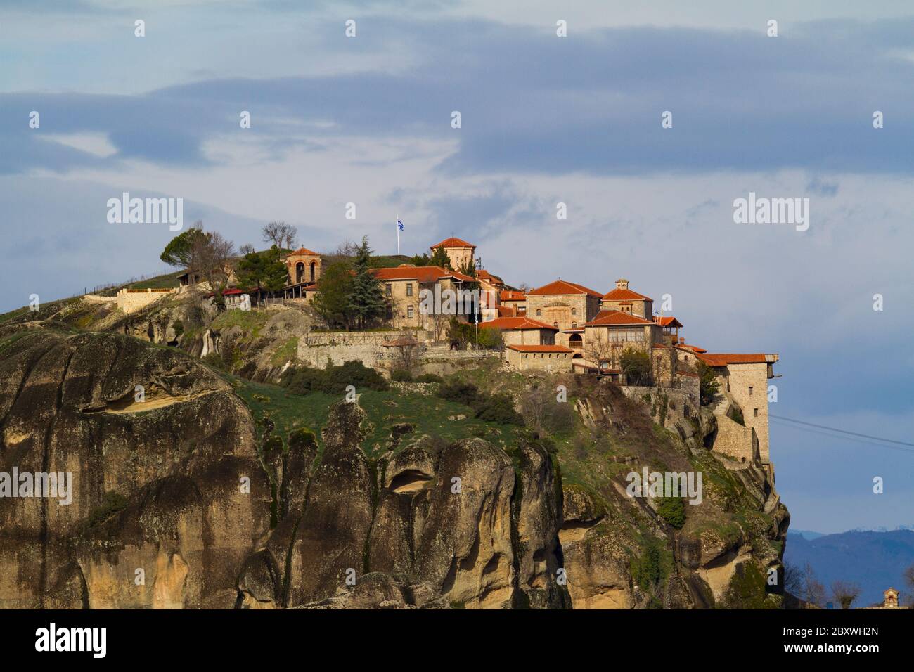 Meteora, Kalampaka, Grecia. Monastero della Santissima Trinità in cima alle colline. Baldings di pietre con tegole del tetto, su una roccia enorme. Il cielo è nuvoloso. Foto Stock