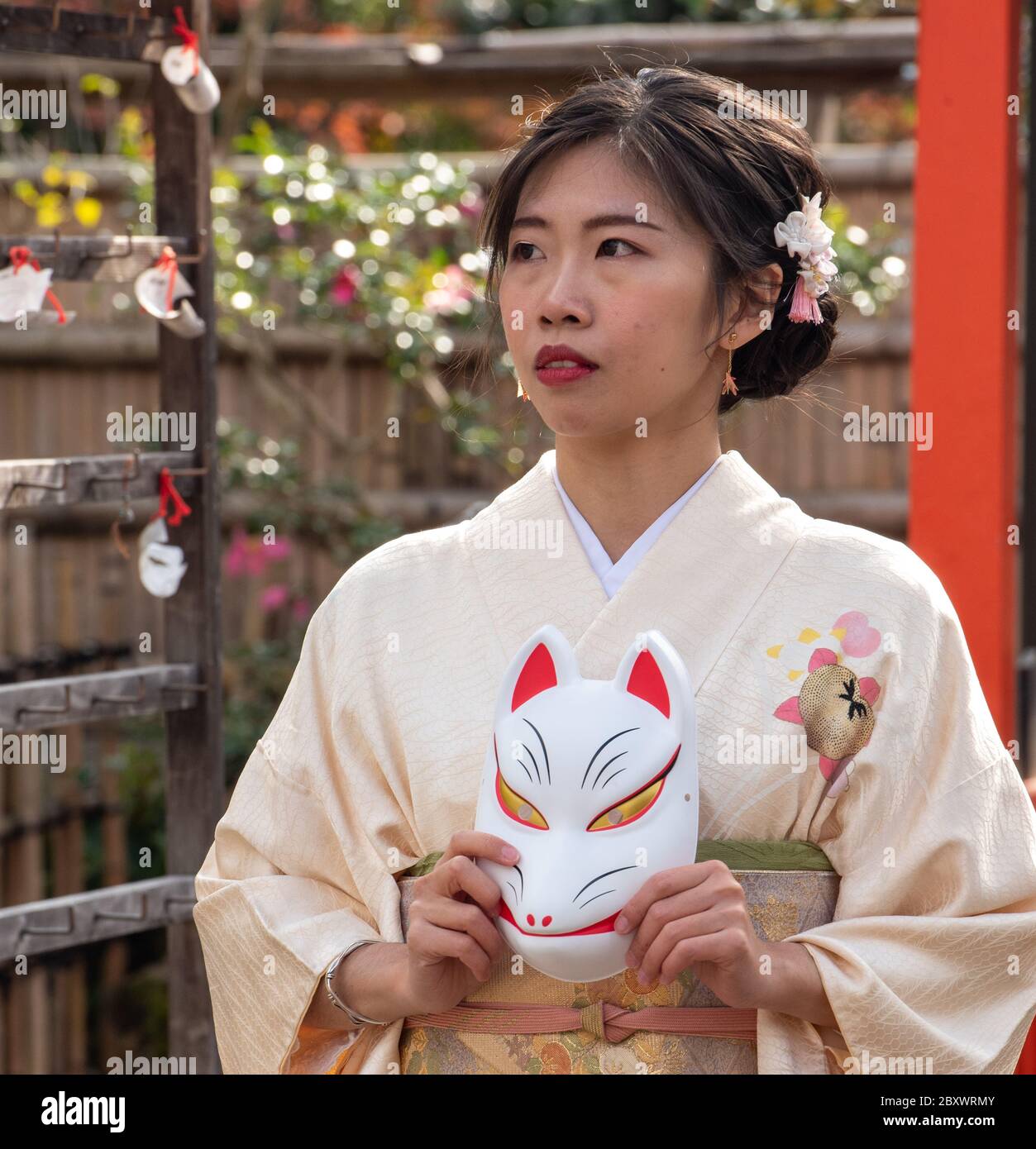 Teen giapponese che indossa kimono tradizionale è in posa con una maschera kitsune. Maschera di volpe giapponese. Queste maschere sono indossate per divertimento, in festival e onorare gli dei Foto Stock