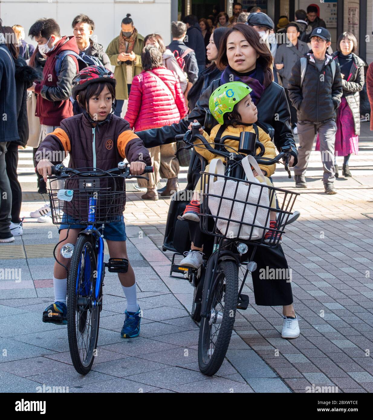 Una madre giapponese con i suoi bambini che cavalcano le biciclette prima di andare a fare shopping al mercato di Ameyoko a pochi metri di distanza. Foto Stock