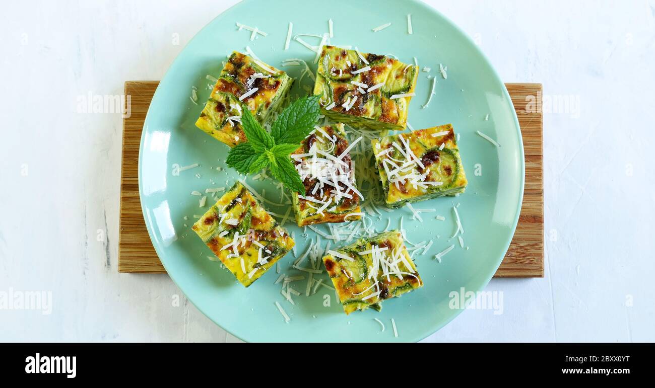 Concetto di finger food. Zucchine frittate con porri, formaggi ed erbe aromatiche su un piatto verde. Vista dall'alto. Foto Stock