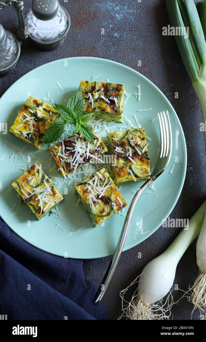 Concetto di finger food. Zucchine frittate con porri, formaggi ed erbe aromatiche su un piatto verde. Vista dall'alto. Foto Stock