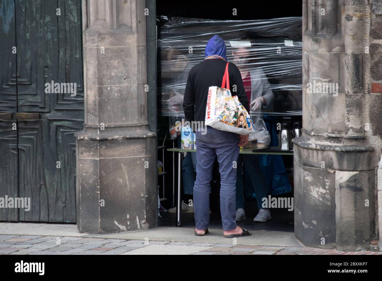 Un uomo singolo attende cibo di carità sulla porta di una chiesa durante la pandemia della corona. Foto Stock