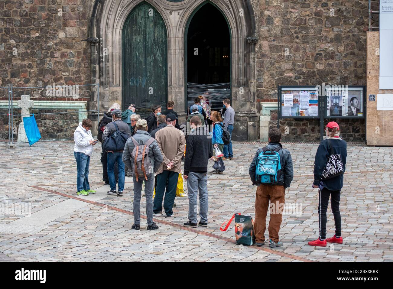 Gruppo di persone in attesa di cibo gratuito in fila davanti a una chiesa di Berlino. Chiesa di Santa Maria, Marienkirche Foto Stock