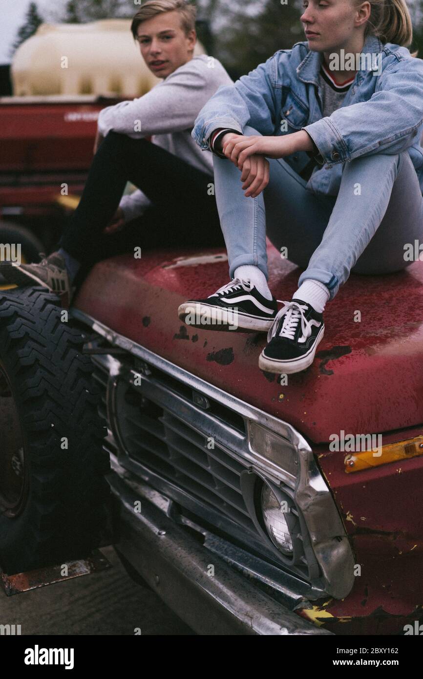 Immagine di un ragazzo e di una ragazza seduti sul cofano di un camion Foto Stock