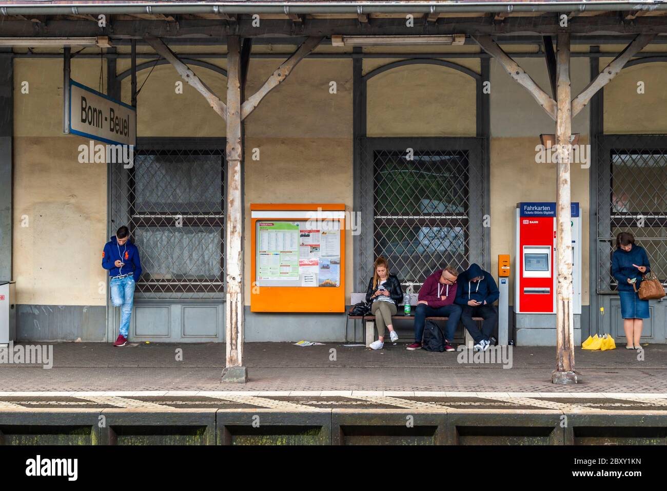 I pendolari sulla piattaforma di Bonn Beuel guardano i loro telefoni cellulari, Germania Foto Stock