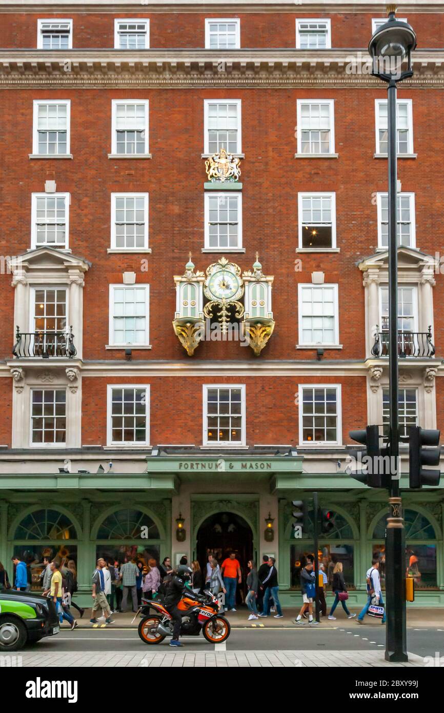La facciata e l'entrata trafficata al grande magazzino Fortnum & Mason in Piccadilly Street a Londra Foto Stock