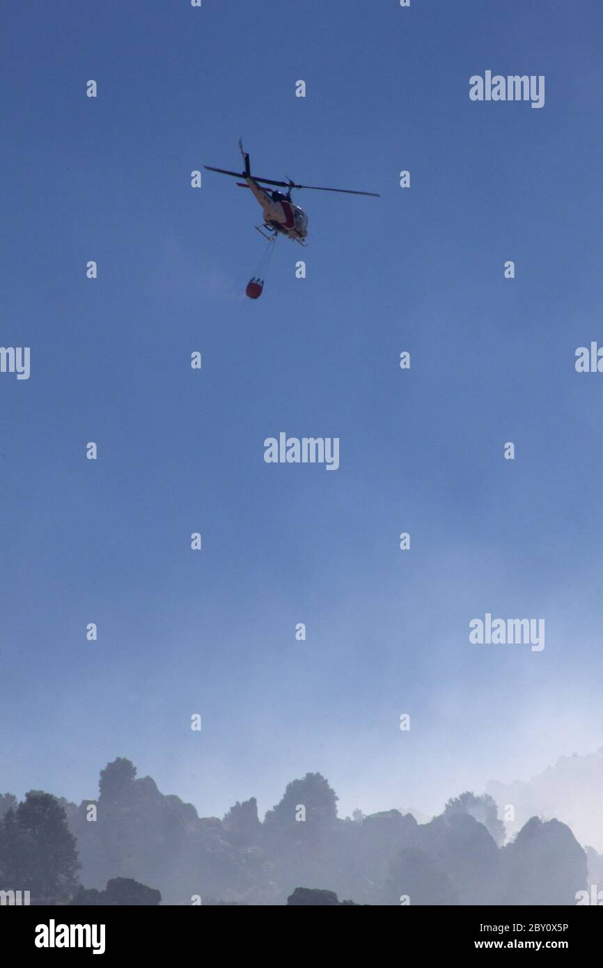 Elicottero antincendio con fumo e la collina Foto Stock