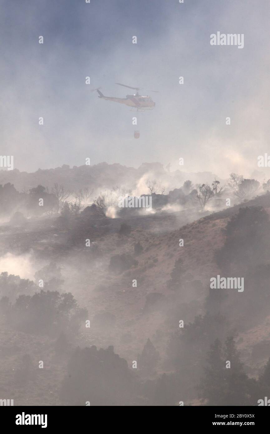 Elicottero antincendio con fumo e la collina Foto Stock