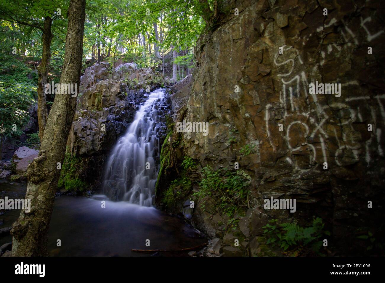 L'acqua scende lungo le cascate Westfield Falls accanto ai graffiti dipinti sulle rocce di Middletown, Connecticut. Foto Stock