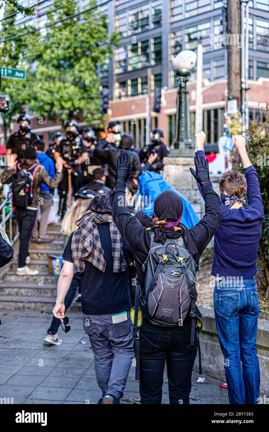 SEATTLE, USA - 6 GIUGNO 2020: Dimostranti con mani in su dopo che la polizia di Seattle ha disperso la folla con i bangs di flash e lo spruzzo del pepe Foto Stock