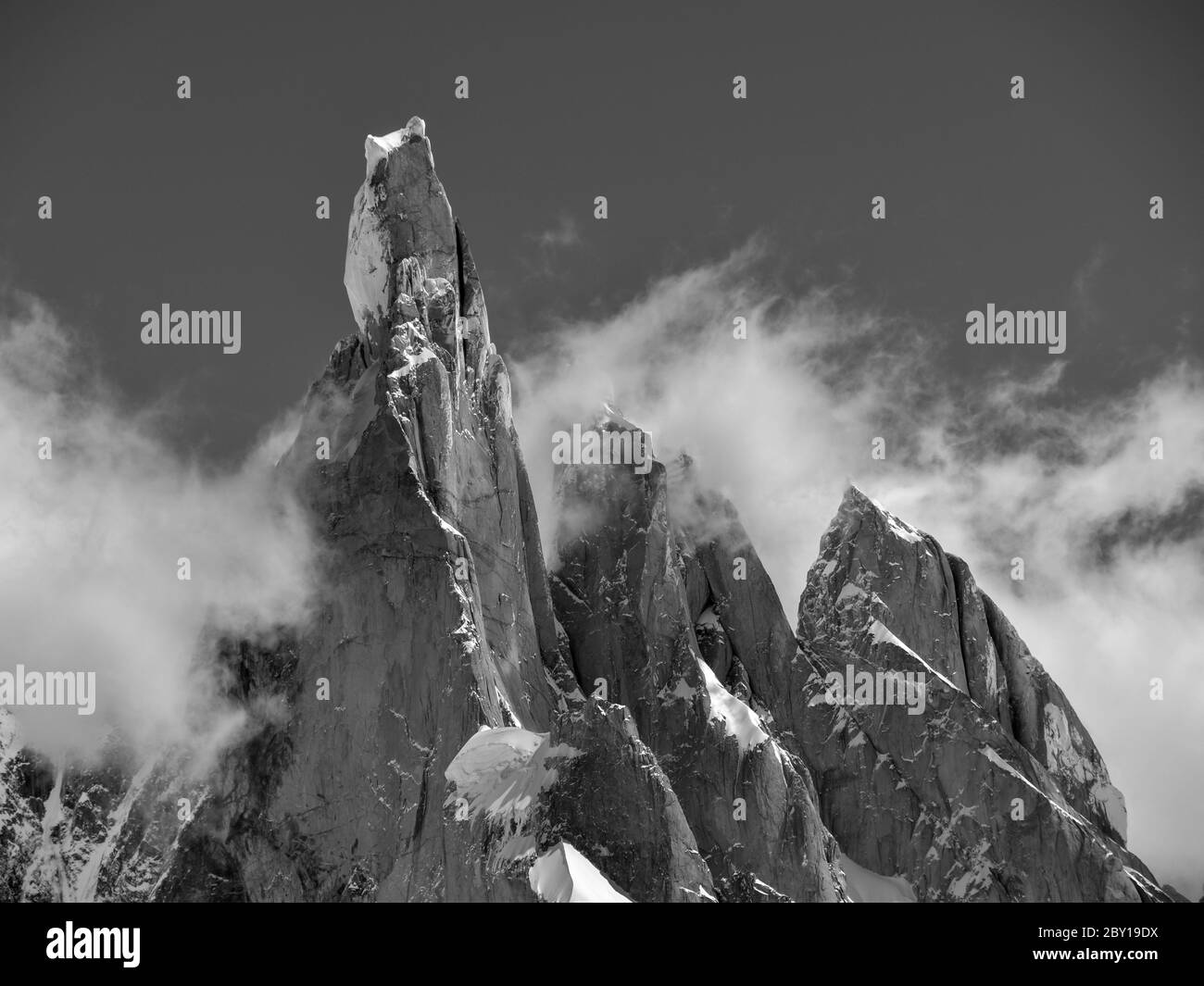 monocromo di cime innevate e nuvole contro cielo limpido, mt. cerro torre e i suoi vicini mt. torre egger e punta herron in los glaci Foto Stock