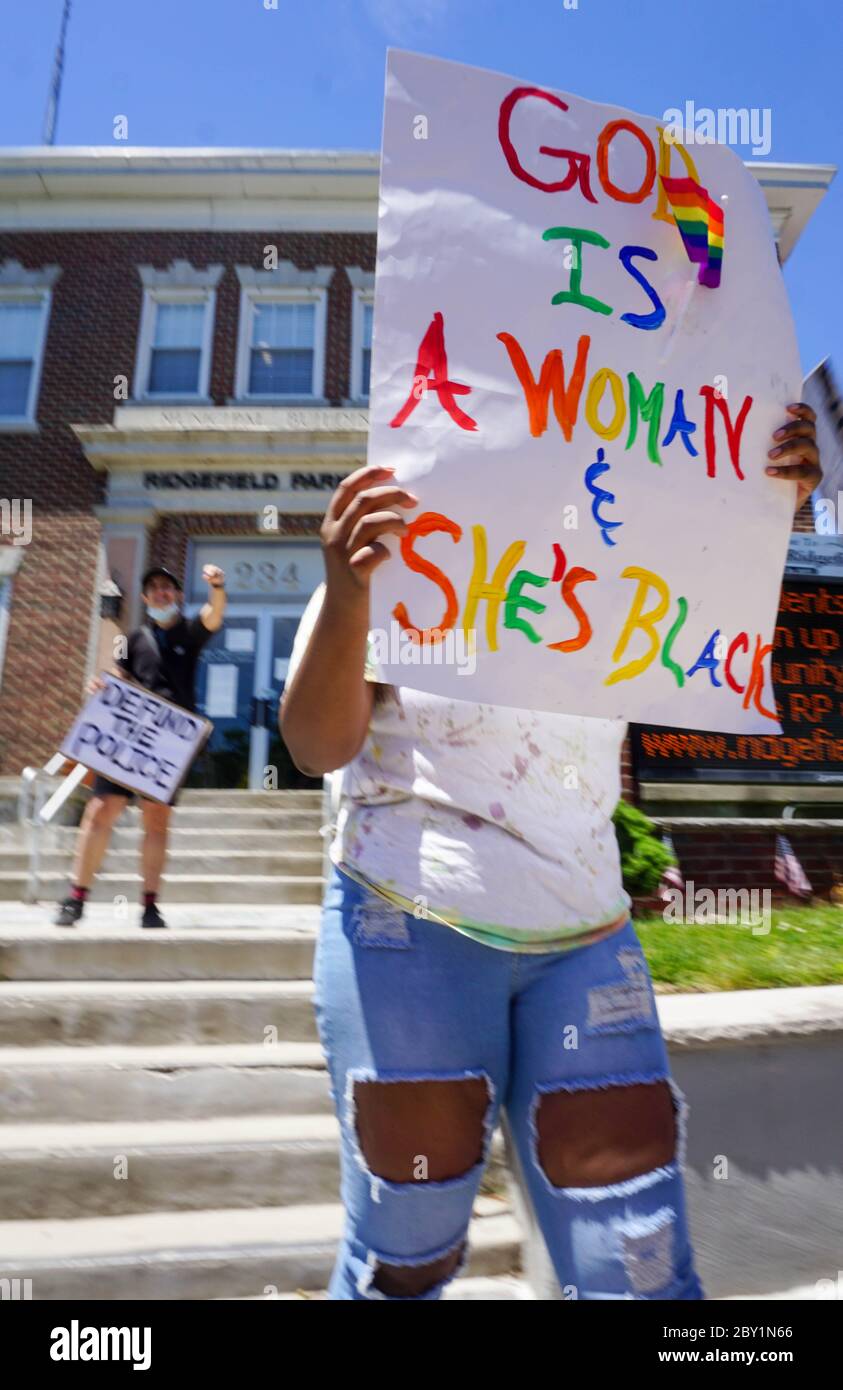 Black Lives Matter protesta George Floyd - Dio è una donna e lei è Nera. Defund la polizia segnali di protesta di fronte all'edificio - Ridgefield Park, BER Foto Stock