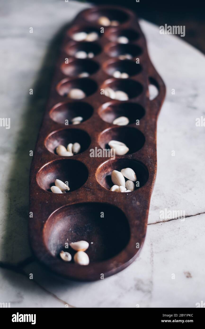 Sungka, gioco di mancala filippina, su un tavolo di pietra di marmo bianco con pezzi di conchiglie. Messa a fuoco selettiva. Orientamento verticale. Foto Stock