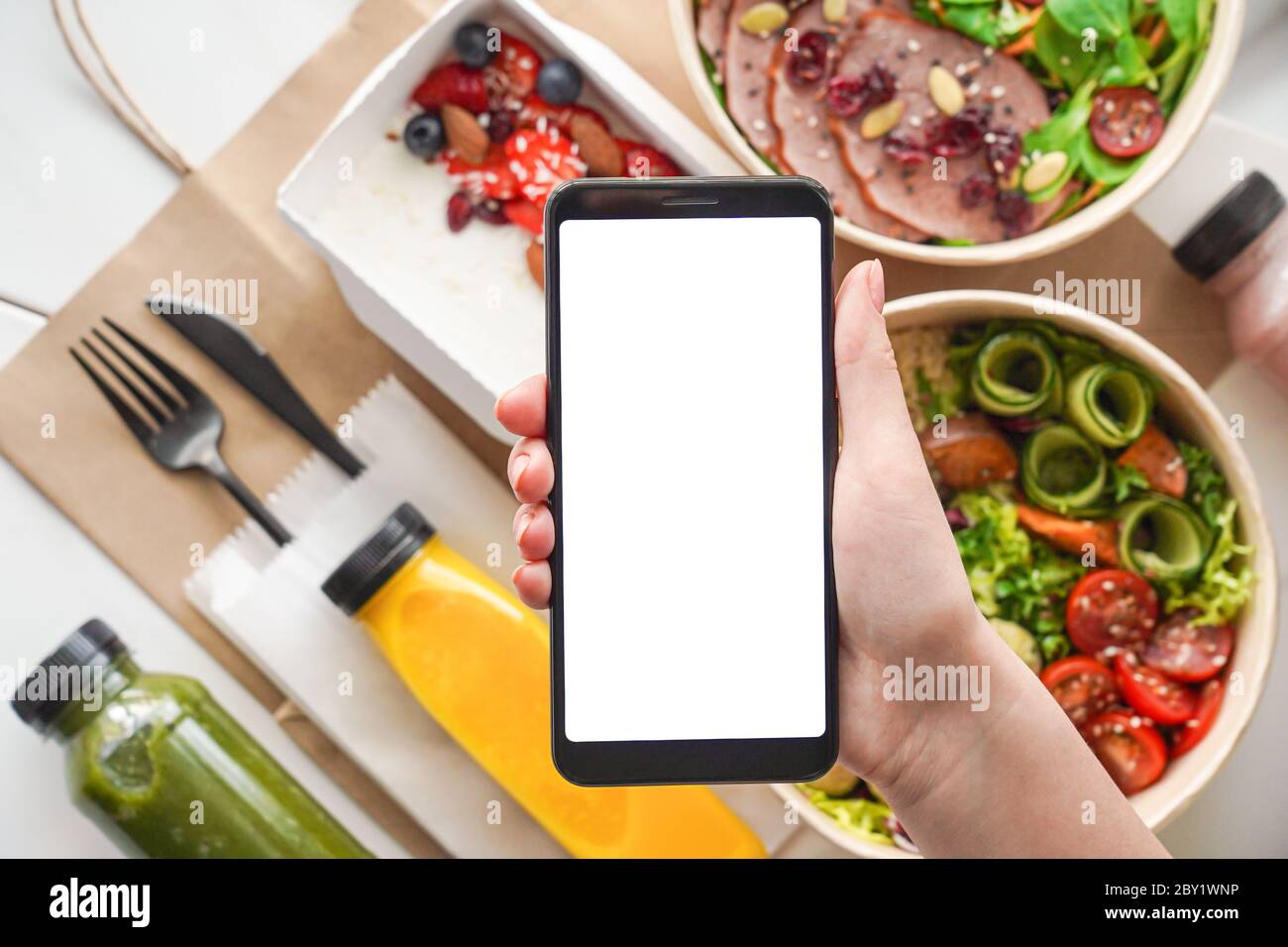La mano della donna tiene il telefono mock up schermo sopra l'app di servizio di consegna delle scatole di cibo. Foto Stock