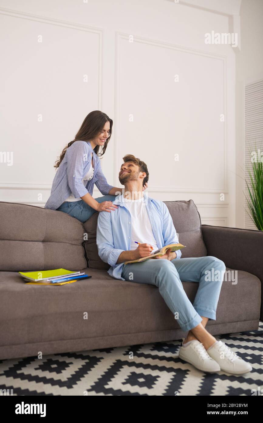 Giovane uomo che studia prima dell'esame e guarda la moglie Foto Stock