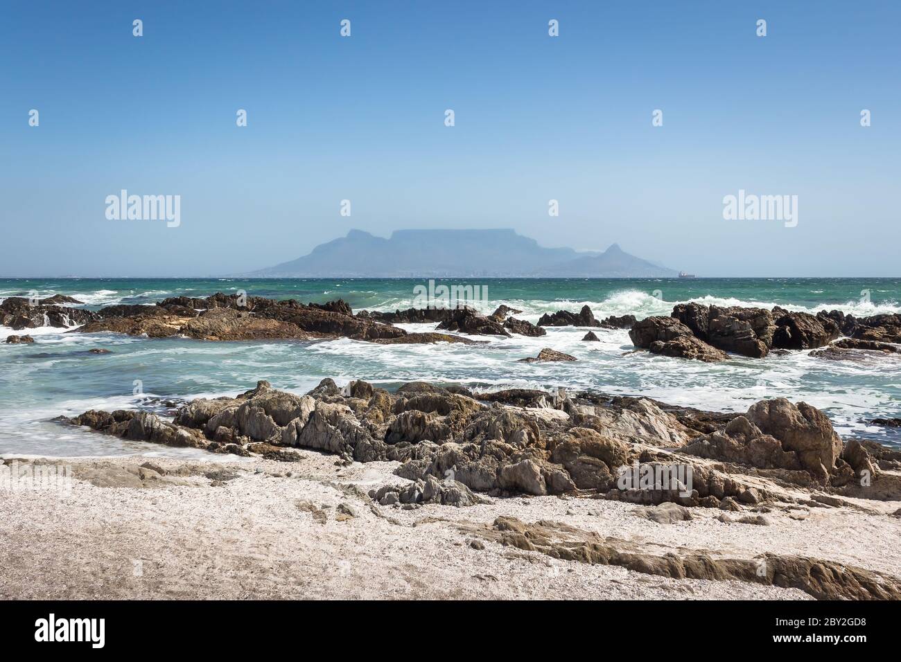 Vista di Table Mountain con spiaggia, oceano e rocce in primo piano, Sudafrica. Foto Stock