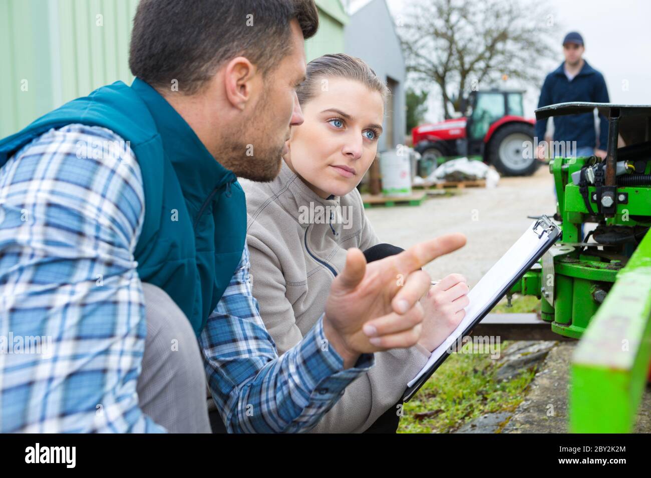 lavoratori di attrezzature agricole che hanno una conversazione Foto Stock