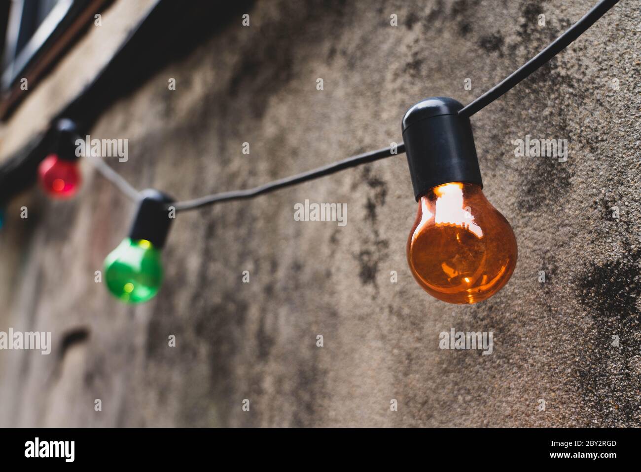 Decorazioni colorate a lampadine appese su una parete in un vicolo. Foto Stock