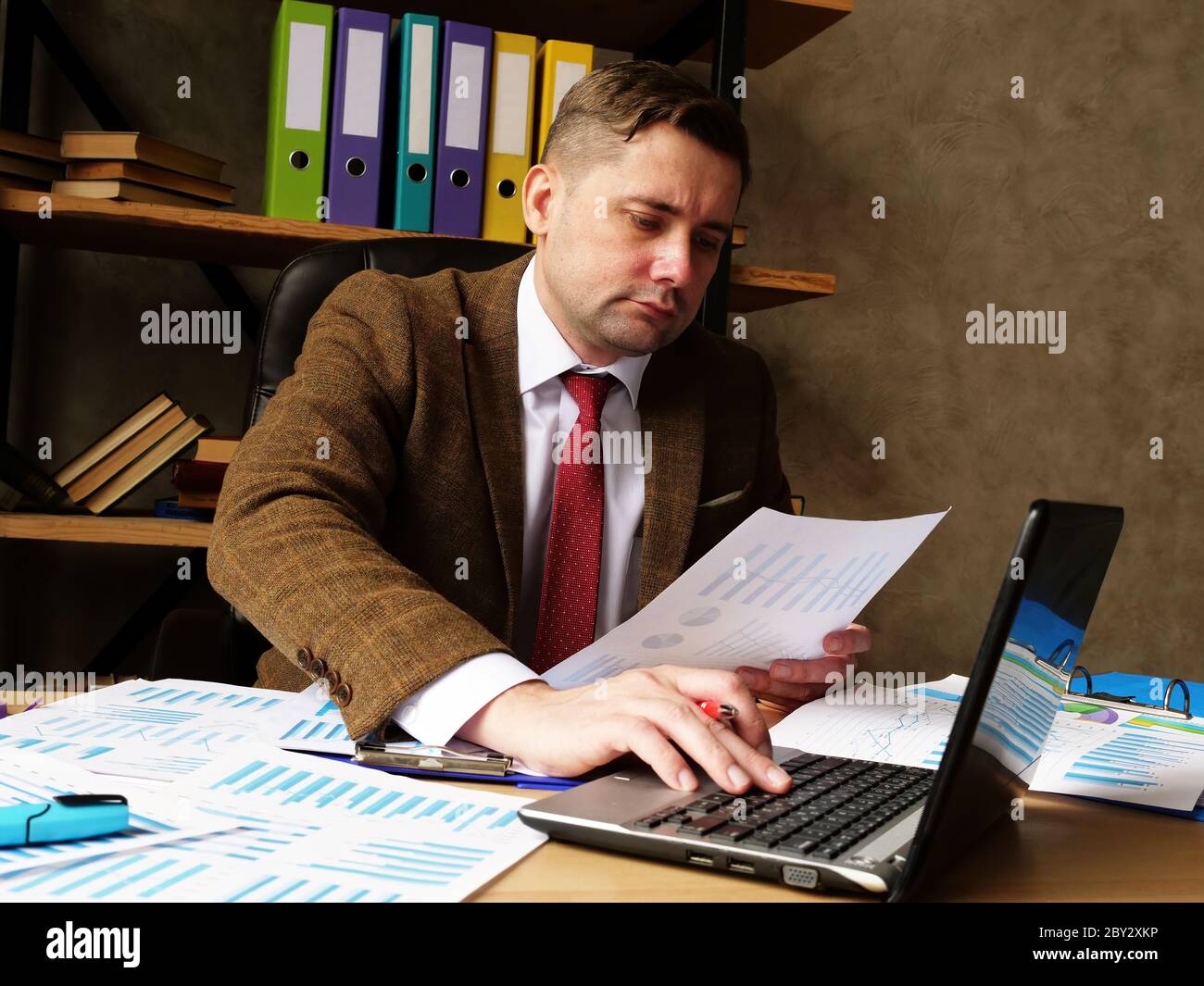 Un contabile lavora con documenti e controlla le prestazioni finanziarie. Lavoro su carta in ufficio. Foto Stock