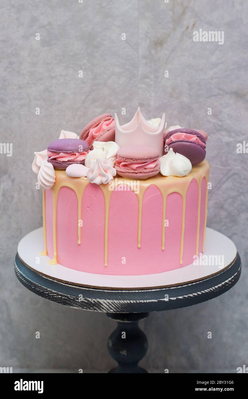 Torta rosa di compleanno per una bambina con corona fondente, cioccolato  bianco fuso, meringa e torta pop su sfondo grigio Foto stock - Alamy