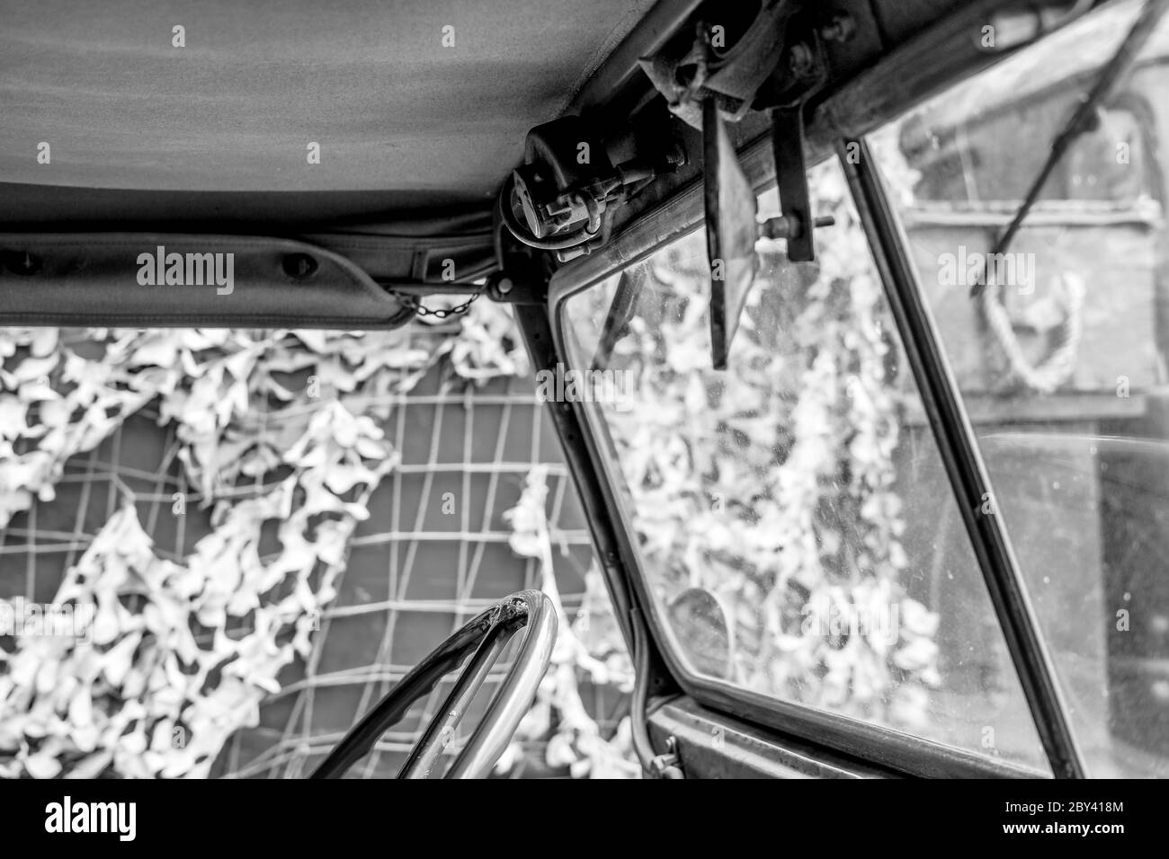 Vista monocromatica di un noto veicolo militare della seconda guerra mondiale con guida a sinistra che mostra parte dello sterzo e la parte superiore in tela. Foto Stock
