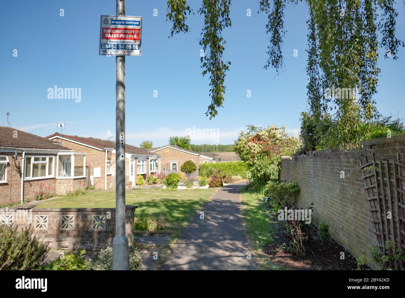 Avviso di prevenzione del crimine visto sopra un lampione in una tenuta di alloggiamento. I bungalow sono utilizzati per anziani e per esigenze speciali. Foto Stock