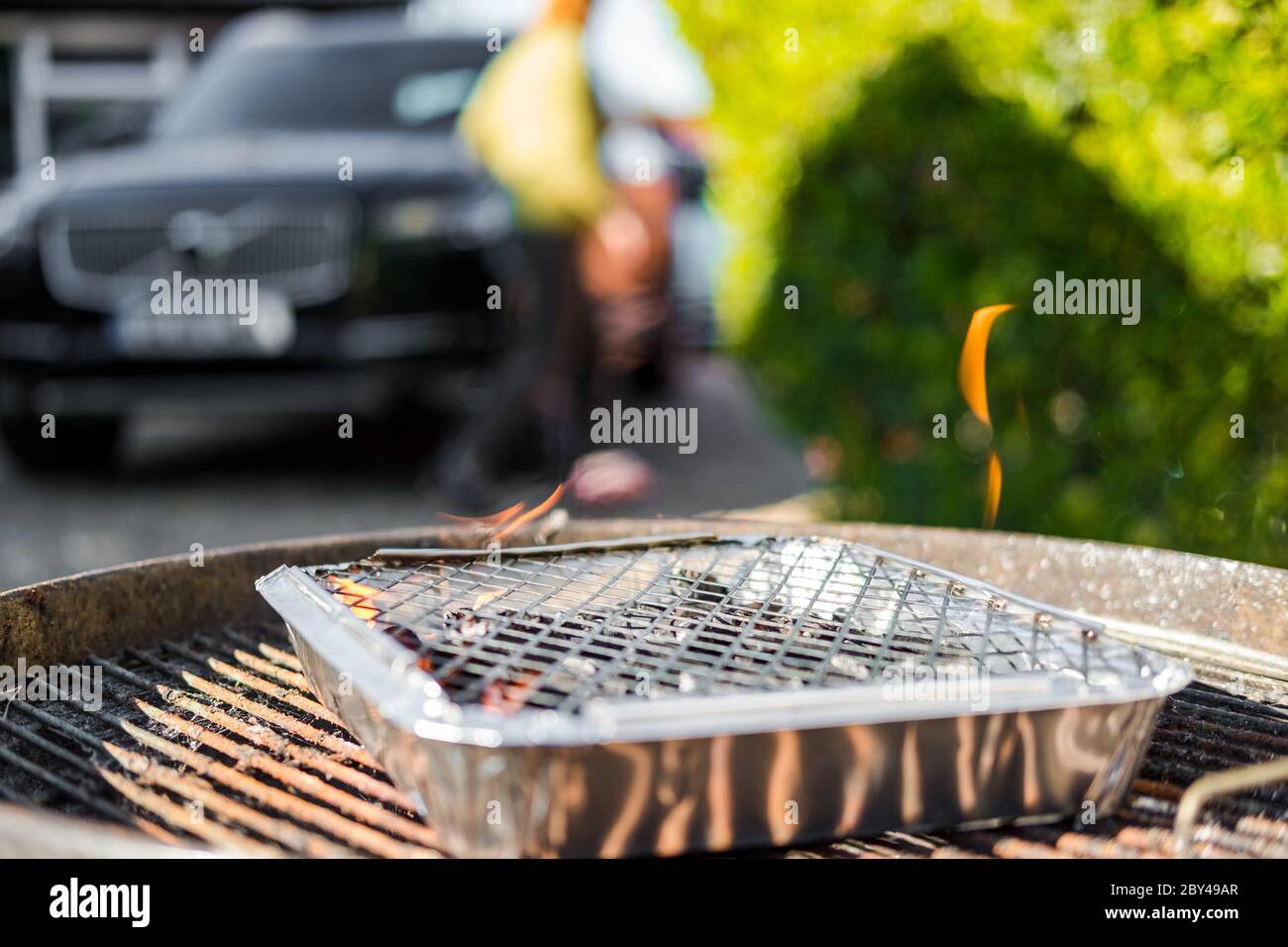 Fuoco superficiale di un barbecue di campeggio visto in un barbecue di dimensioni complete. Si vedono le fiamme emesse, pronte per la cottura della carne. Visto in un grande giardino. Foto Stock