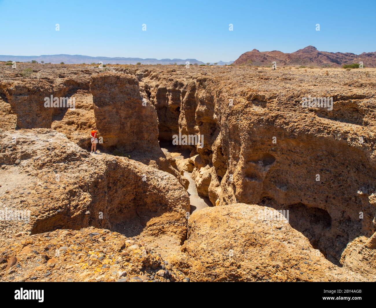 Donna che si trova sul bordo del Sesriem Canyon a Sossusvlei, deserto del Namib, Namibia Foto Stock
