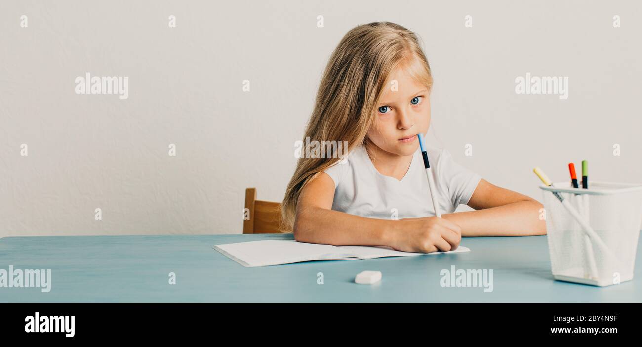 bionda ragazza si siede a un tavolo e scrive in un notebook Foto Stock