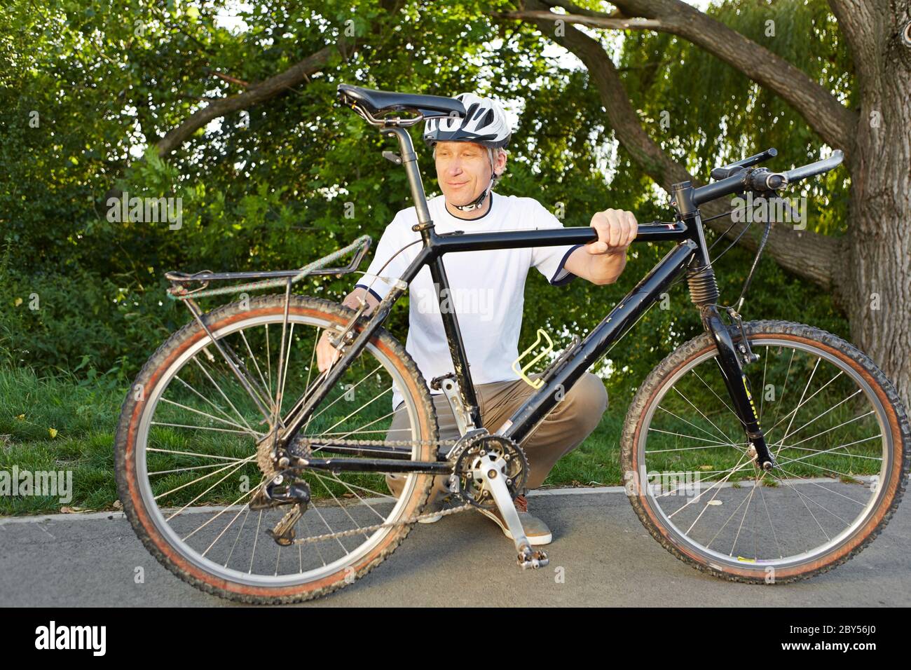 Uomo con guasto bici ripara la sua bici su una strada Foto Stock