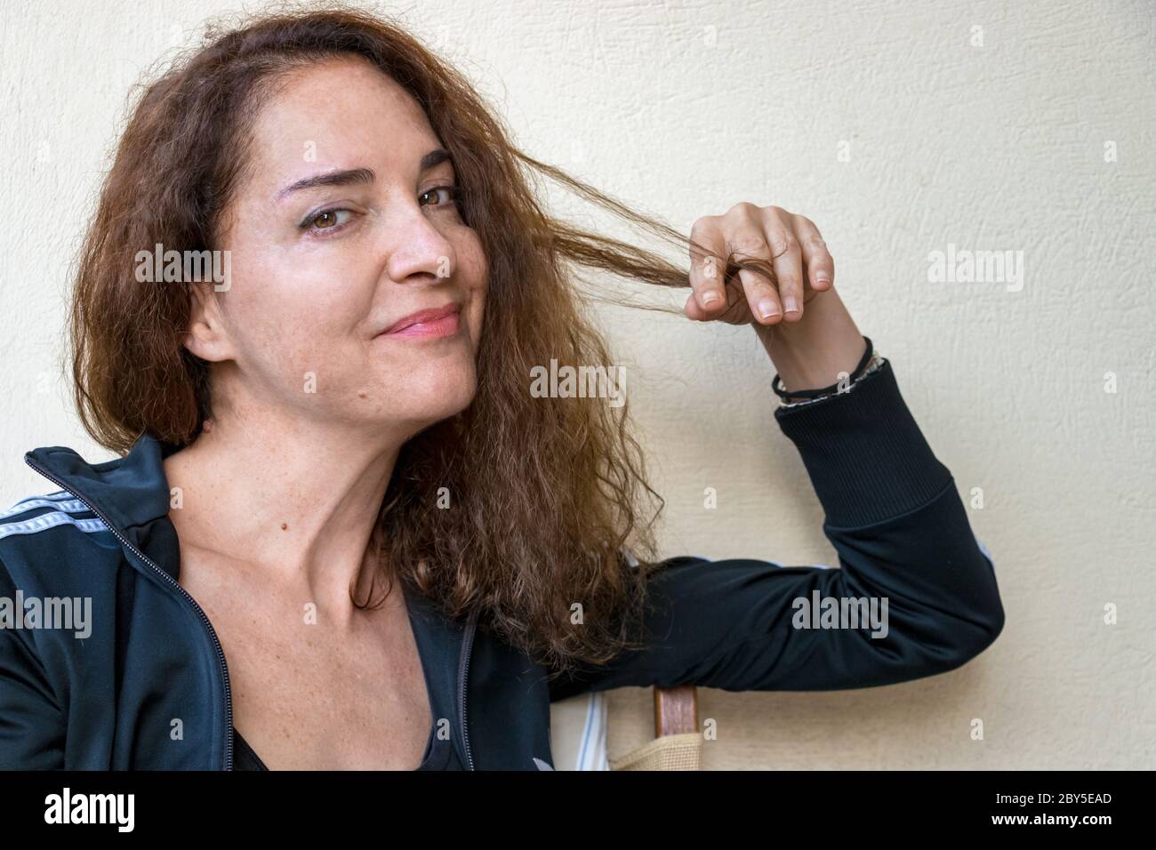 Ritratto di una donna matura in forma con la mano sui capelli guardando la fotocamera. Foto Stock