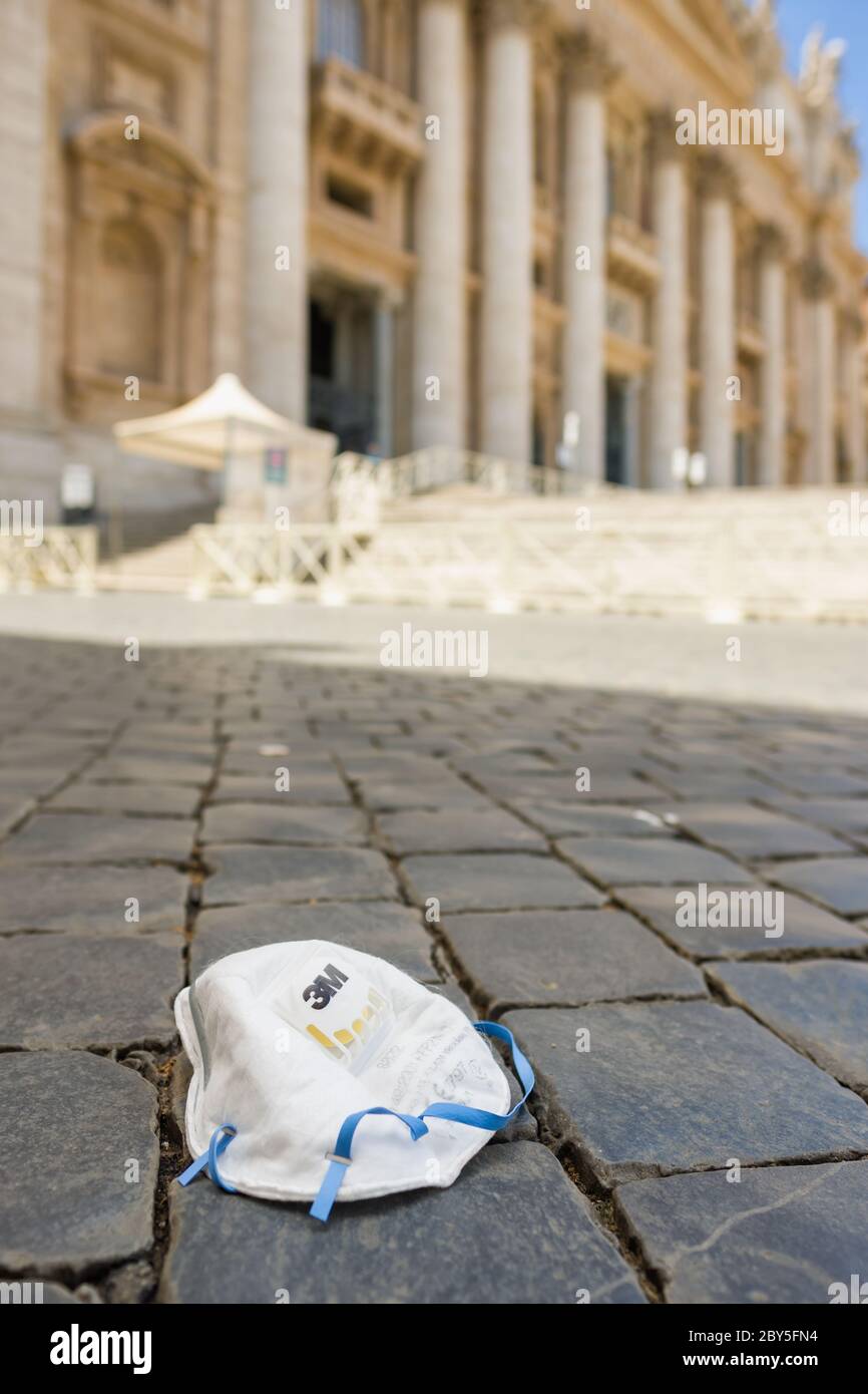 Maschera medica usata su pietre di pavimentazione di un st vuoto. Piazza Peters nella città del Vaticano durante la pandemia di Covid 19 Foto Stock