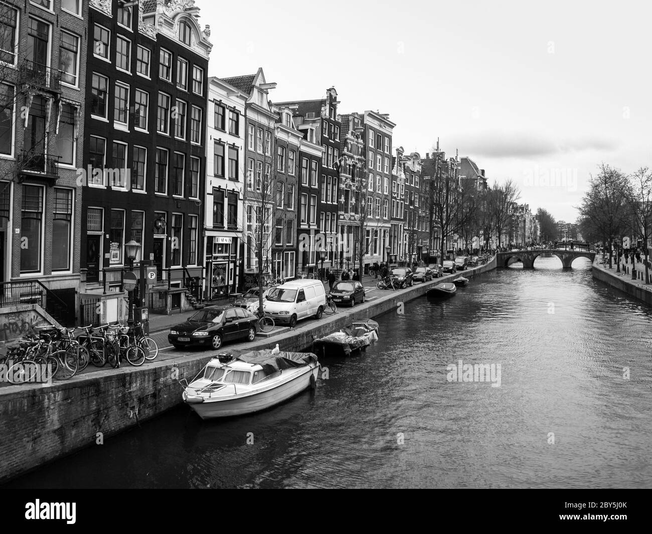 Tipico canale d'acqua - Gracht - e case strette lungo di esso nel centro di Amsterdam, Paesi Bassi, immagine in bianco e nero Foto Stock