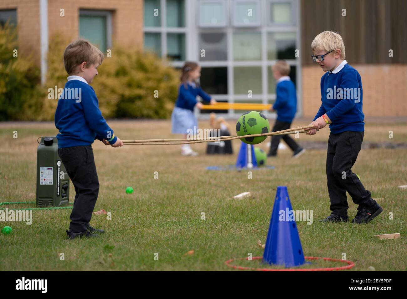 Staffordshire, Gran Bretagna. 8 Giugno 2020. Gli studenti di accoglienza della Landywood Primary School utilizzano bastoni per mantenere la distanza sociale mentre partecipano a un programma educativo del personaggio del Commando Joe, a Staffordshire, Gran Bretagna, l'8 giugno 2020. Il programma di Commando Joe è un servizio di sviluppo e supporto educativo di grande personalità per le scuole di tutto il Regno Unito, che ispira gli studenti con competenze di team-building, carattere e resilienza. Aiuta gli studenti a far fronte alla reintegrazione nell'ambiente scolastico. Credit: Jon Super/Xinhua/Alamy Live News Foto Stock