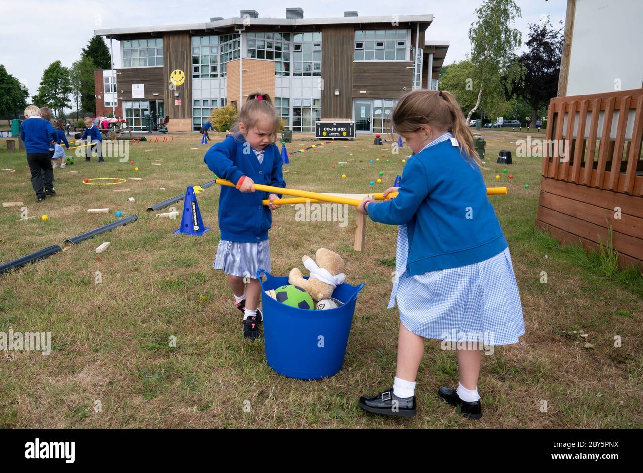 Staffordshire, Gran Bretagna. 8 Giugno 2020. Gli studenti di accoglienza della Landywood Primary School utilizzano bastoni per mantenere la distanza sociale mentre partecipano a un programma educativo del personaggio del Commando Joe, a Staffordshire, Gran Bretagna, l'8 giugno 2020. Il programma di Commando Joe è un servizio di sviluppo e supporto educativo di grande personalità per le scuole di tutto il Regno Unito, che ispira gli studenti con competenze di team-building, carattere e resilienza. Aiuta gli studenti a far fronte alla reintegrazione nell'ambiente scolastico. Credit: Jon Super/Xinhua/Alamy Live News Foto Stock