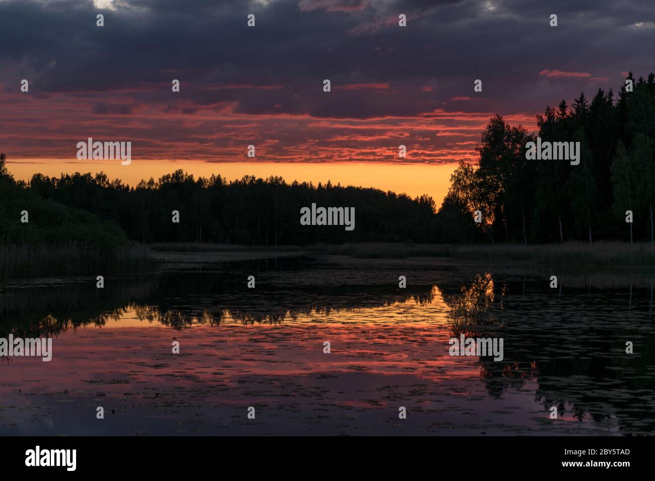 Le nuvole del tramonto si riflettono nelle calme acque specchio del lago. Splendido tramonto con riflessi sul lago sullo sfondo. Tramonto con rosso a. Foto Stock