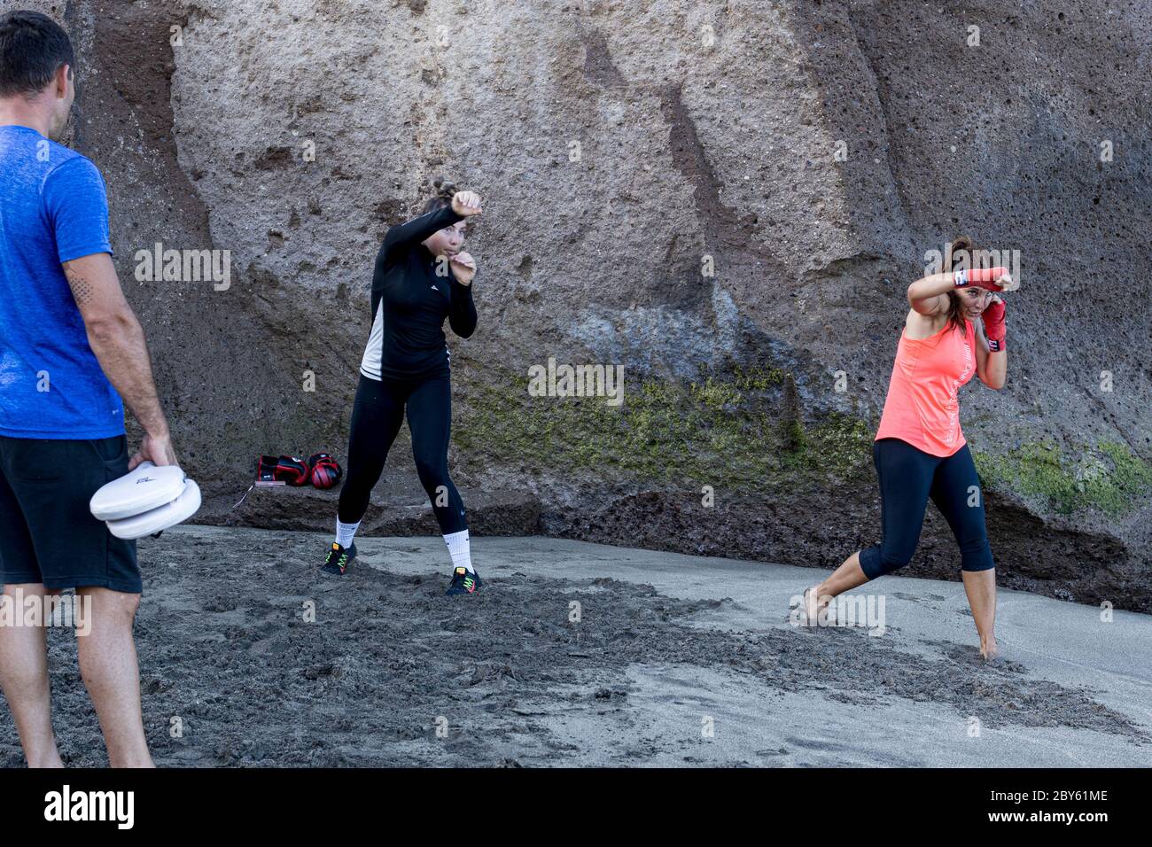 Addestramento della boxer femminile con le pagaie sparring sulla spiaggia presto nella mattina durante la fase 3 de-escalation dello stato di emergenza a causa di Covid 19, pandemia del virus di Corona. L'isola sta lentamente tornando al tipo di normale con le spiagge e alcune strutture per lo svago aperte. Playa del Duque, Costa Adeje, Tenerife, Isole Canarie, Spagna. 9 giugno 2020. Foto Stock