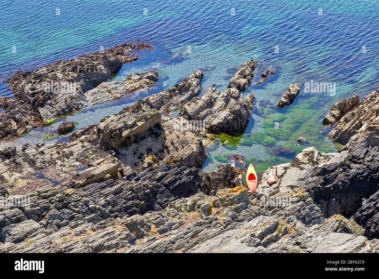 Guardando giù su un canoista prendere il sole sulle rocce a Port Erin, Isola di Man con acqua limpida Foto Stock