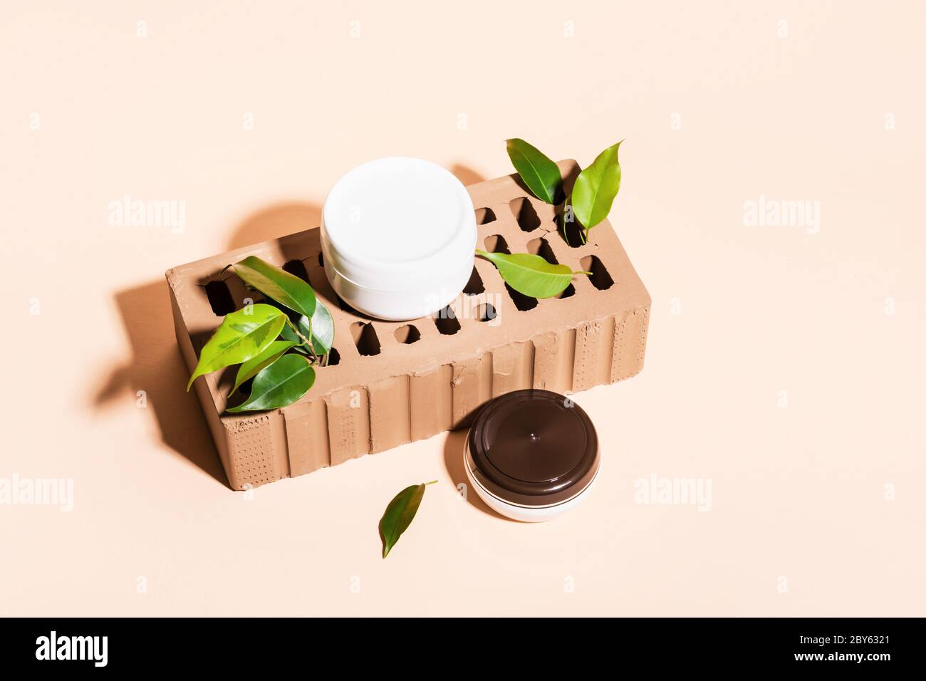 Mockup Jars per marcare a caldo ed etichettare. Prodotti cosmetici allestita su supporto in mattoni e foglie verdi. Concetto minimo di bellezza creativa. Foto Stock