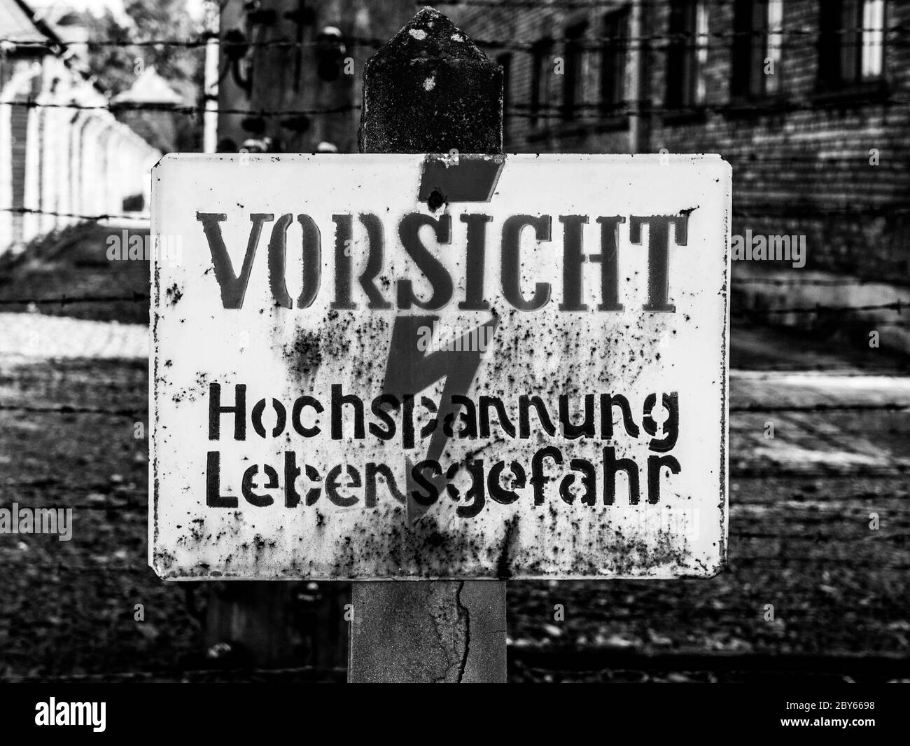 Cartello di allarme sul recinto elettrico nel campo di concentramento di Oswiecim, Polonia. Immagine in bianco e nero. Foto Stock