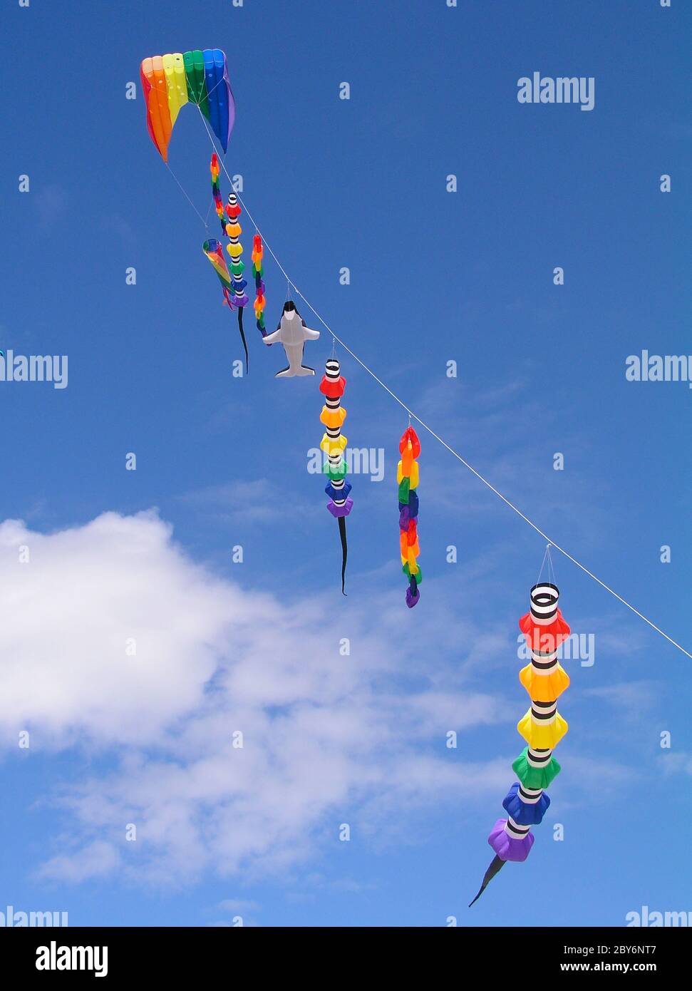 Una collezione di aquiloni multicolore contro un cielo blu luminoso. Foto Stock