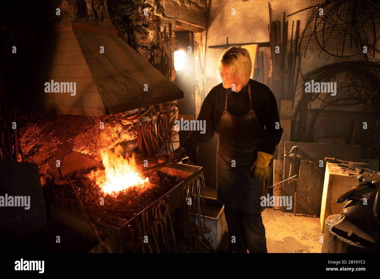 Fabbro femminile che lavora alla fiamma della fonderia Foto Stock